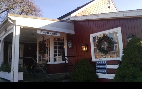 A red building with a sign reading "Entrance," decorated with wreaths and a flag-themed display on the porch.