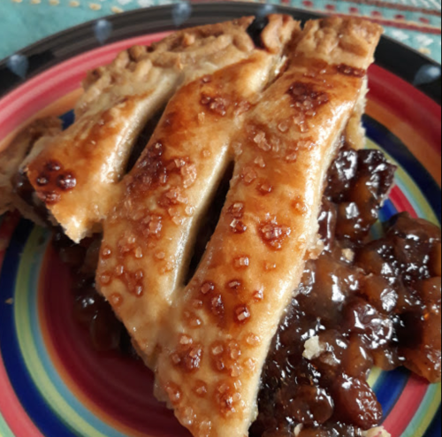 A slice of pie with a golden, flaky crust and a shiny, sweet filling on a colorful plate.