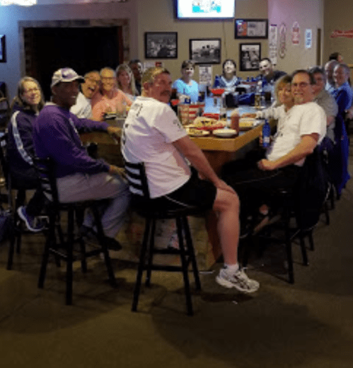 A group of people sitting around a table in a casual restaurant, smiling and enjoying their time together.