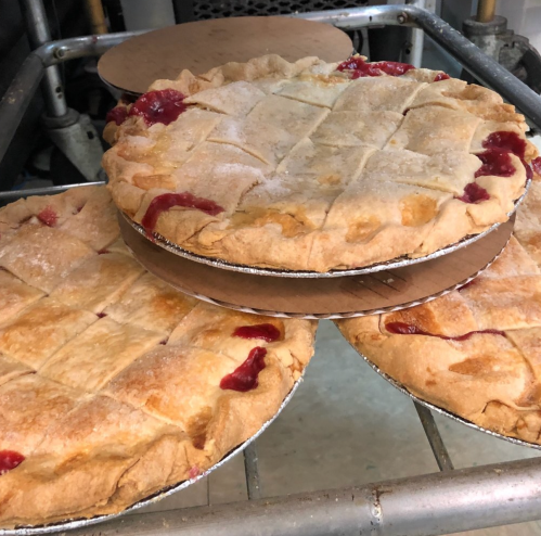 Three freshly baked fruit pies with lattice crusts, resting on a cooling rack.