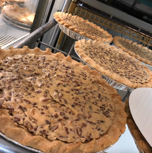 Freshly baked pecan pies cooling on a rack, showcasing their golden crust and nutty filling.