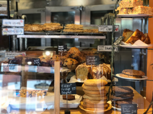 A display case filled with various baked goods, including cookies, cakes, and pastries, with price tags visible.