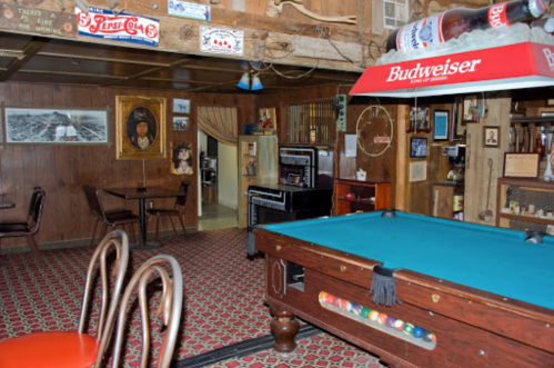 A cozy, vintage game room with a pool table, wooden decor, and nostalgic memorabilia on the walls.