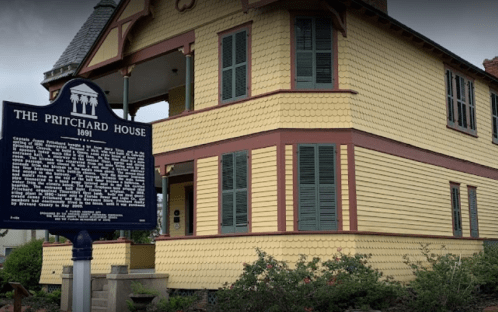 Historic Pritchard House, built in 1891, featuring yellow siding and a historical marker in front.