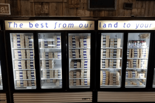 A display of refrigerated boxes in a store, with the text "The best from our land to your" above the shelves.