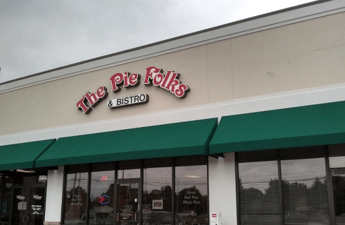 Sign for "The Pie Folks & Bistro" with green awnings on a storefront. Cloudy sky in the background.