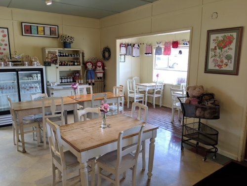 Cozy café interior with wooden tables, chairs, and decorative items, featuring a bright, inviting atmosphere.