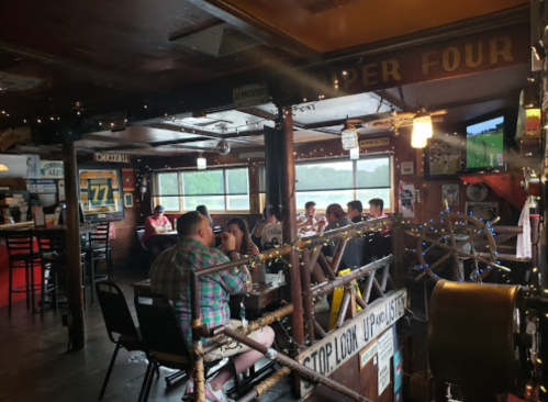 A cozy restaurant interior with patrons dining, rustic decor, and large windows overlooking a scenic view.