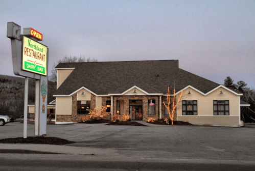 A cozy restaurant with a dairy bar, featuring outdoor lights and a welcoming "Open" sign at dusk.