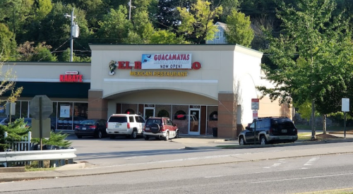 Exterior of a Mexican restaurant named "El Guacamayas," with cars parked outside and trees in the background.