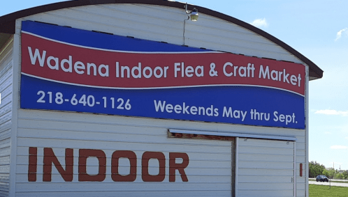 Sign for Wadena Indoor Flea & Craft Market, featuring contact info and operating hours from May to September.
