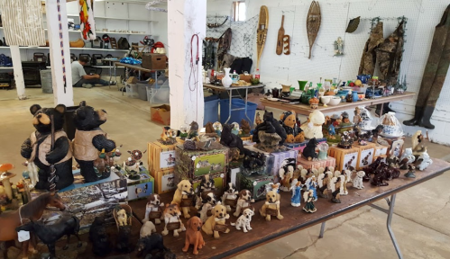 A display of various animal figurines and collectibles on tables in a spacious indoor market.