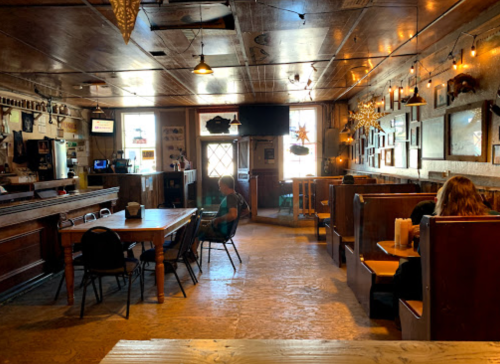A cozy restaurant interior with wooden decor, tables, and booths, featuring warm lighting and a relaxed atmosphere.