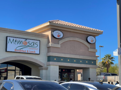 Exterior of Mimosa's Gourmet restaurant, featuring a sign for breakfast and lunch, under a clear blue sky.