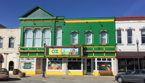 Colorful building with green exterior and yellow accents, featuring "OZ" signage and vibrant murals on the ground floor.