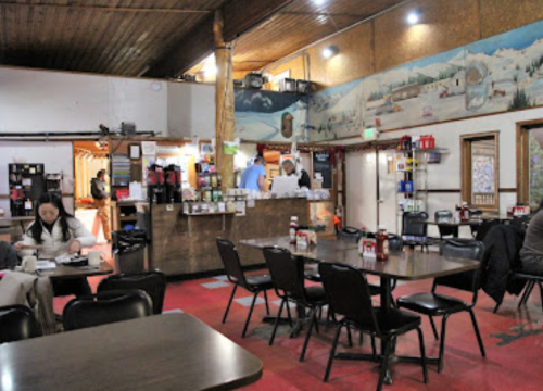 Cozy diner interior with wooden accents, tables, and a mural of snowy mountains in the background.