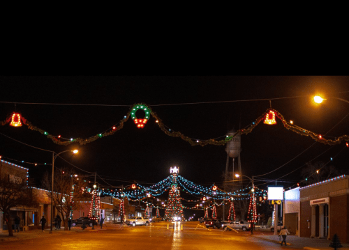 A festive street at night, adorned with colorful Christmas lights and decorations, creating a cheerful holiday atmosphere.