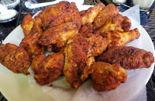 A large platter of crispy, golden-brown fried chicken wings on a white paper lining.