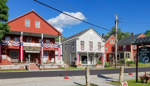 Charming Vermont village scene featuring colorful buildings decorated with patriotic bunting on a sunny day.