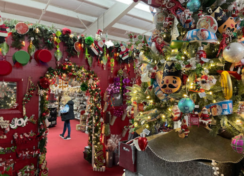 A festive shop filled with holiday decorations, including a decorated tree and colorful ornaments, set against a red backdrop.