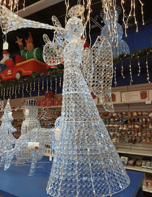 A large, illuminated angel decoration made of clear materials, surrounded by festive holiday decor in a store.