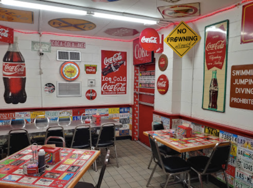 A retro diner with Coca-Cola decor, colorful tables, and vintage license plates on the walls.