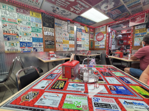 A vibrant diner interior featuring walls and tables adorned with colorful license plates and advertisements.