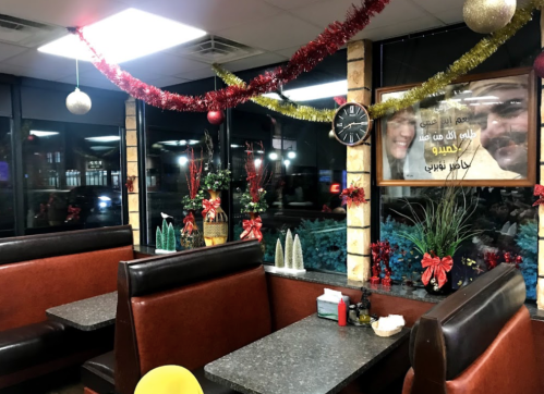 Cozy diner interior decorated for the holidays with festive garlands, plants, and a clock on the wall.