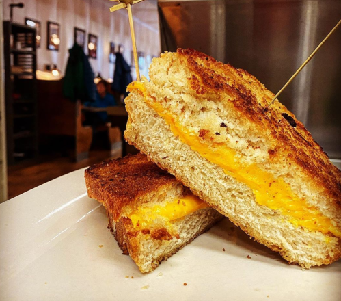 A golden-brown grilled cheese sandwich, cut in half, showcasing melted cheese between slices of toasted bread.