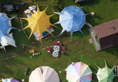 Aerial view of colorful tents set up on green grass, with a circular seating area in the center.
