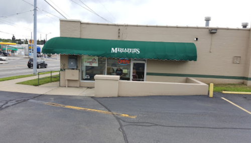 A storefront with a green awning labeled "Michaels," featuring an "Open" sign and a parking area.