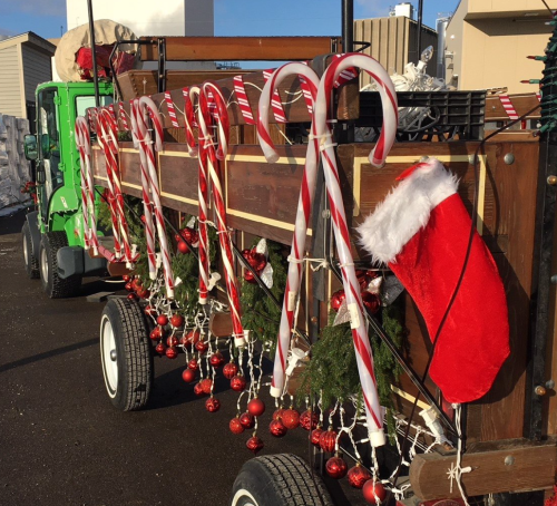 A decorated wagon with candy canes, Christmas ornaments, and a Santa hat, ready for the holiday season.