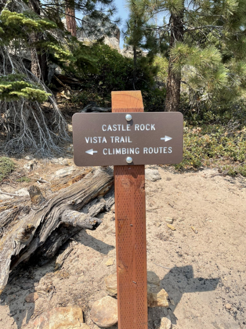 Signpost indicating directions to Castle Rock, Vista Trail, and Climbing Routes in a forested area.