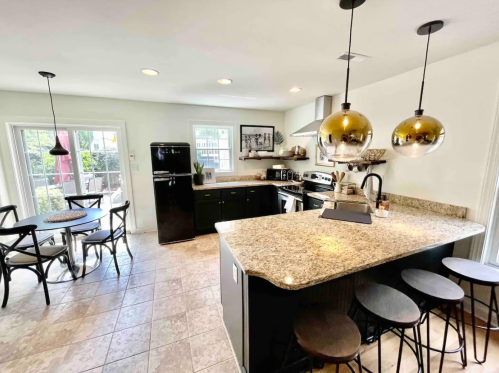 Modern kitchen with granite countertops, black appliances, and a dining area featuring a round table and chairs.