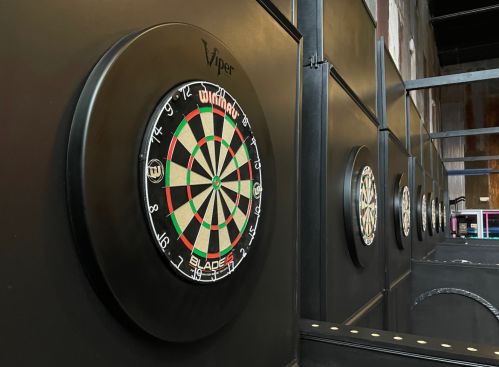 A row of dartboards on a black wall in a game room, featuring Viper and Winmau branding.