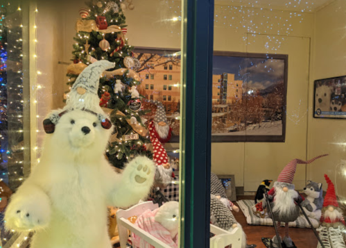 A festive window display featuring a polar bear, Christmas tree, and whimsical gnome decorations.