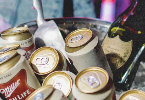 A bucket filled with ice, featuring cans of Miller beer and a bottle of champagne.