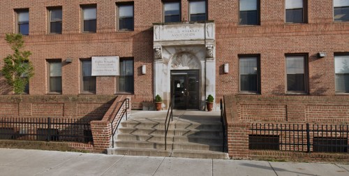 Entrance of the Phyllis Wheatley Association building, featuring steps and a decorative archway.