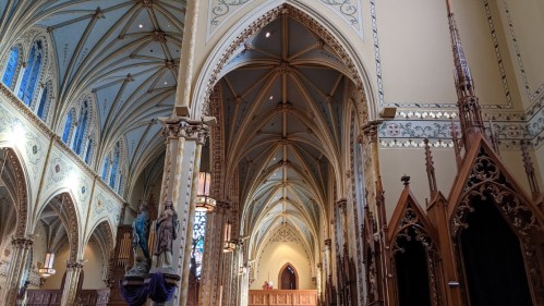 Interior of a grand church featuring ornate arches, stained glass windows, and intricate woodwork.