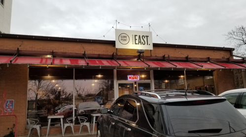 Exterior of a restaurant named "Can't Pore" with a sign for "EAST." Cars parked outside under a cloudy sky.