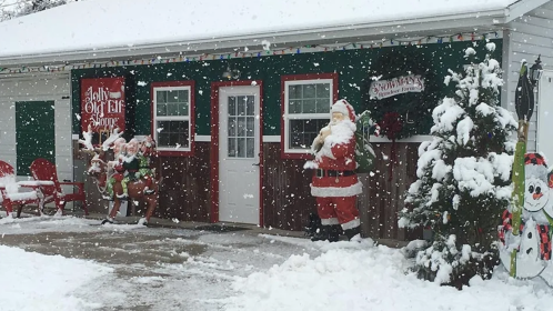 A snowy scene featuring a festive building decorated for Christmas, with Santa and reindeer figures outside.