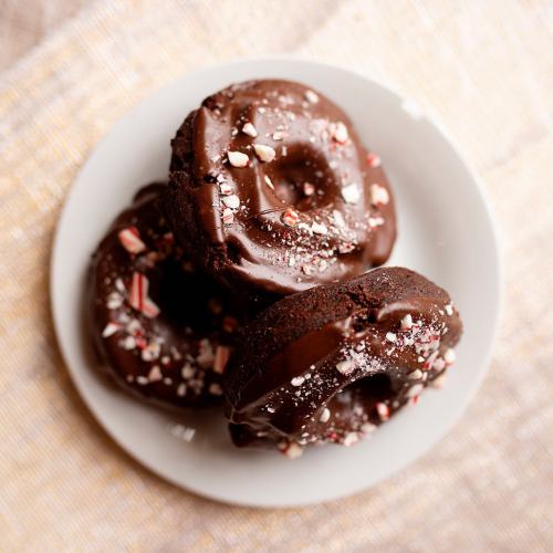 A plate of chocolate donuts topped with crushed peppermint pieces.
