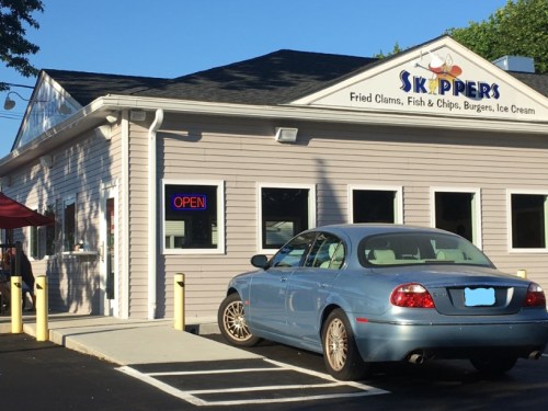 A restaurant named Skippers with a sign that says "Open," featuring a parked car in front.