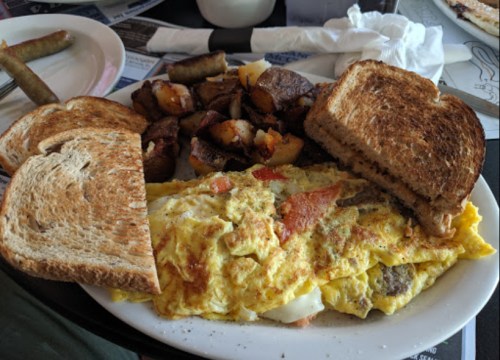 A hearty breakfast plate featuring an omelette, toast, and seasoned potatoes.