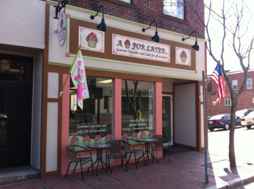 Exterior of "A For Later," a cupcake shop with outdoor seating, colorful signage, and an American flag.