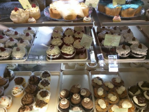 A display case filled with various cupcakes and desserts, featuring different flavors and decorative toppings.