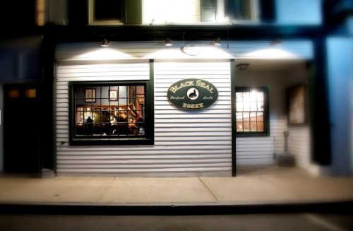 Exterior of a restaurant named "Black Seal" with a sign, warm lighting, and a welcoming atmosphere.