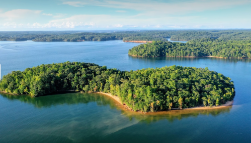 Aerial view of lush green islands surrounded by calm blue water under a clear sky.