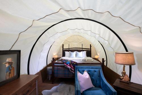 Cozy tent interior featuring a bed, decorative pillows, a lamp, and a framed picture on a wooden dresser.