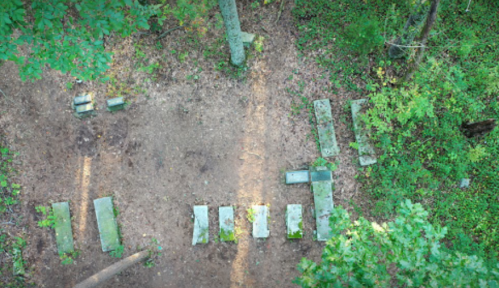 Aerial view of a clearing in a forest with arranged stone blocks and surrounding trees.